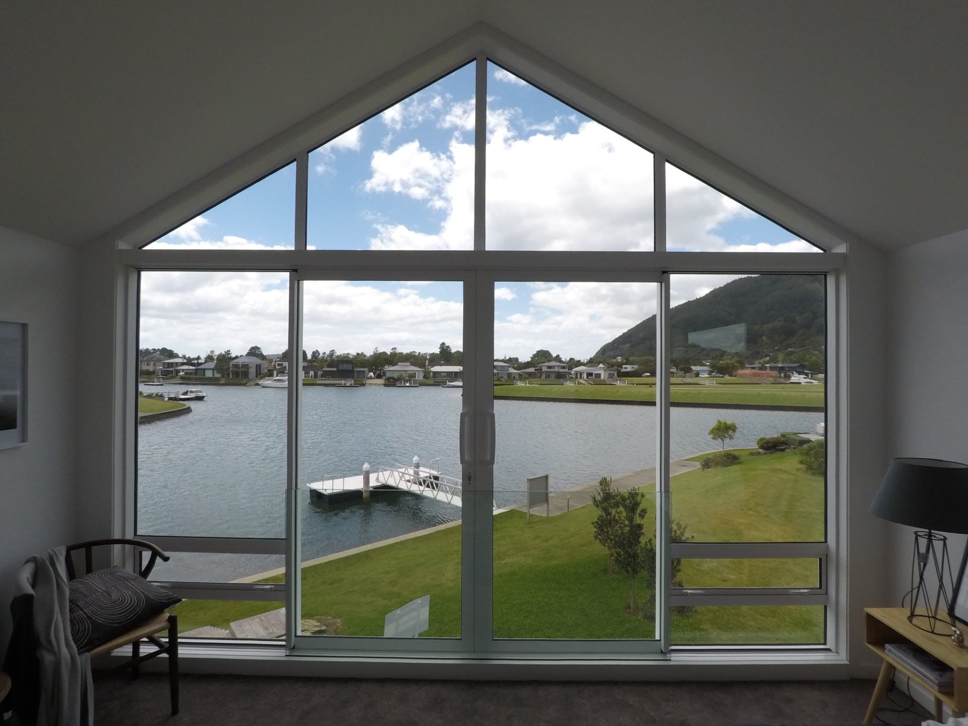 Raking gable-end window framing a waterfront outlook above sliding doors